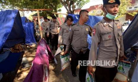 Sejumlah petugas kepolisian saat memberikan bantuan kepada pengungsi di Posko pengungsian Lapangan Masjid Agung Darussalam , Palu, Sulawesi Tengah, Jumat (5/10).