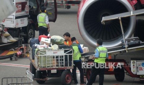 Petugas masukan barang milik penumpang ke bagasi pesawat di Bandara Internasional Soekarno,-Hatta, Tanggerang,Banten, Kamis (7/2).