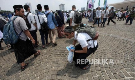 Peserta reuni aksi 212 mengumpulkan sampah seusai Reuni Aksi 212 di Lapangan Monumen Nasional, Jakarta, Ahad, (2/12).