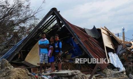 Satu keluarga berdiri di depan rumahnya yang rubuh di  wilayah Petobo, Kabupaten Sigi, Sulawesi Tengah, Kamis (11/10).