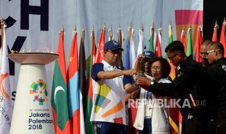 Gubernur DKI Jakarta Anies Baswedan (kiri) bersama Ketua Delegasi Api Obor Celerina Judisari (kedua kiri) menyalakan api obor Asian Games 2018 ke tinder box pada prosesi Torch Relay di Balai Kota DKI Jakarta, Jakarta Pusat, Kamis (16/8).