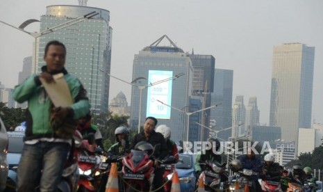 Sejumlah pengendara motor berhenti dengan latar belakang suasana gedung bertingkat yang diselimuti asap polusi di kawasan Sudirman, Jakarta, Senin (29/7).