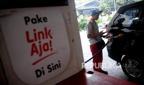 Petugas membantu konsumen melakukan transaksi pembayaran menggunakan layanan keuangan berbasis elektronik LinkAja di SPBU Kuningan, Jakarta, Senin (1/7).