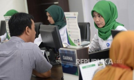 Petugas Badan Penyelenggara Jaminan Sosial (BPJS) Kesehatan melayani warga di kantor BPJS Kesehatan Cabang Jakarta Selatan, Senin (2/9).