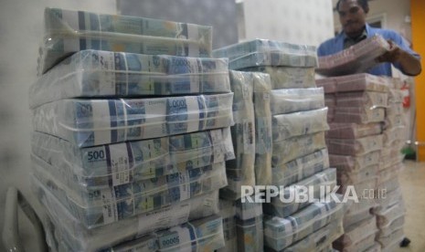 Petugas menata tumpukan uang rupiah di Cash Center Bank Mandiri,Jakarta, Senin (23/7).