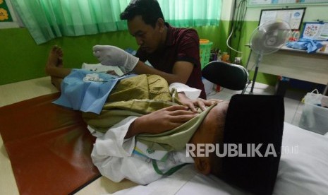 Anak menutup matanya saat sedang disunat. Tindakan sirkumsisi alias sunat dianjurkan karena ada manfaatnya bagi kesehatan. 