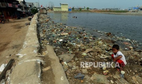 Anak-anak bermain di dekat tanggul pengaman pantai yang bocor di kawasan Muara Baru, Jakarta Utara, Selasa (11/12).