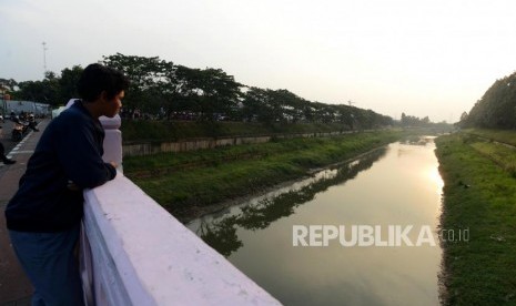 Warga melihat aliran sungai Banjir Kanal Timur di kawasan Duren Sawit, Jakarta Timur, Kamis (25/10).