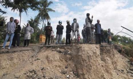 Warga berdiri di jalan batas kampung yang hilang terseret liquifaksi atau pencairan tanah akibat gempa bumi di Desa Jono Oge, Sigi, Sulawesi Tengah, Senin (8/10).