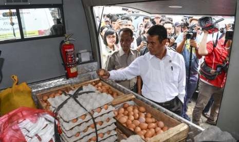 Menteri Pertanian Amran Sulaiman (kanan) didampingi Kepala Badan Ketahanan Pangan Agung Hendriadi (kedua kiri) memeriksa telur ayam yang akan didistribusikan untuk operasi pasar di Toko Tani Indonesia Centre, Jakarta Selatan, Kamis (19/7).