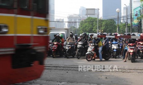 Menunggu. Pengendara kendaraan roda dua  menunggu teerbukanya pintu perlintasan kereta sebidang di Jalan K.H Mansyur, Jakarta, Rabu (1/11).