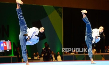 Atlet putri Taekwondo Indonesia Defia Rosmaniar (kiri) berdampingan dengan Atlet putri Taekwondo Malaysia Khim Wen Yap pada babak final perorangan Poomsae pada event Invitation Torunament Asian Games 18 di Jakarta, Sabtu (10/2).