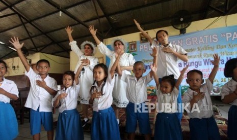 Ibu guru kembar Rian dan Rossi belajar menari bersama para siswa di Sekolah Kartini Kampung Lodan, Jakarta, Senin (26/11).