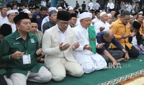 Pasangan Calon Gubernur dan Wakil Gubernur Jawa Barat Ridwan Kamil dan Uu Ruzhanul Ulum dan massa pendukungnya berdoa bersama, di halaman parkir lapangan Sidolig, Kota Bandung, Selasa (9/1).