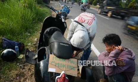 Pemudik membetulkan sepeda motor yanh mogok saat melakukan perjalanan mudik di kawasan  Bekasi, Jawa Barat, Sabtu, (9/6).