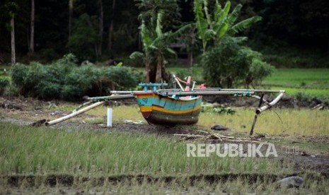 Perahu nelayan yang terdampar di area persawahan di Desa Way Uli, Kalianda, Lampung Selatan, Selasa (25/12).