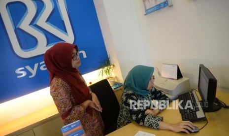 Petugas melayani transaksi nasabah di kantor layanan BRI Syariah, Jakarta.