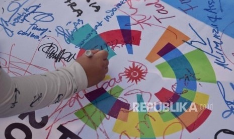 Warga menandatangani banner dukungan untuk Asian Games 2018 saat  hari bebas kendaraan bermotor di kawasan Bundaran Hotel Indonesia, Jakarta, Ahad (22/7).