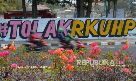 Pengendara melintas di area mural Tolak RUU RKUHP di Rawamangun, Jakarta Timur, Senin (30/9/2019).