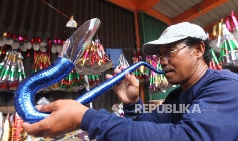 Pedagang mengecek suara terompet kertas yang sudah jadi di Kawasan Glodok, Jakarta, Rabu (27/12).