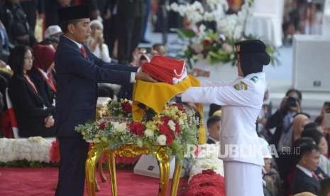 Presiden Republika Indonesia, Joko Widodo (kiri) menerima  duplikat bendera sang merah putih dari  Paskibraka Zanita Tahta  dalam upacara penurunan bendera sang merah putih di hari kemerdekaan Republik Indonesia ke 73 di  Istana Merdeka, Jakarta, Jumat (17/8).