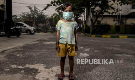 Nabila memakai masker untuk menghalau kabut asap kebakaran hutan dan lahan di Pekanbaru, Riau, Kamis (19/9).