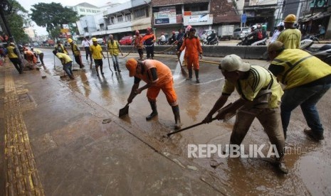 Petugas PPSU dan Bina Marga membersihkan lumpur pascabanjir di Ruas Jalan Jatinegara Barat, Jakarta, Rabu (7/2).