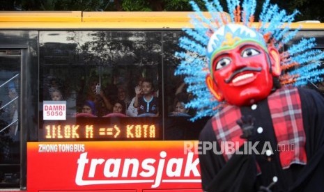 Warga menyaksikan dari bus Transjakarta saat parade Festival Jakarnaval 2018 yang melintas di Jalan Medan Merdeka Barat, Jakarta.