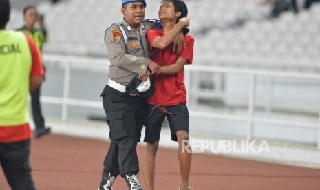 Petugas keamanan mengamankan seorang suporter timnas Indonesia yang berusaha masuk kedalam lapangan saat pertandingan Kualifikasi babak kedua Piala Dunia 2022 zona Asia melawan Malaysia di Stadion Gelora Bung Karno, Senayan, Jakarta, Kamis (5/9).