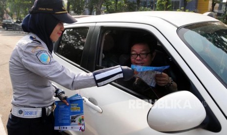 Petugas Dinas Perhubungan membagikan brosur sosialisasi uji coba perluasan ganjil genap di kawasan Pancoran, Jakarta Selatan, Senin (2/7).