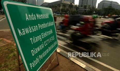 Pengendara motor melintas didekat plang sosialisasi kawasan pemberlakuan tilang elektronik di Jalan MH Thamrin, Jakarta, Jumat (30/11).