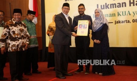 Menteri Agama Lukman Hakim Saifuddin menyerahkan kartu nikah kepada pasangan suami istri seusai peresmian Aplikasi Pencatatan Nikah (SIMKAH) Web dan Kartu Nikah di Auditorium Kementerian Agama, Jakarta, Kamis (8/11).