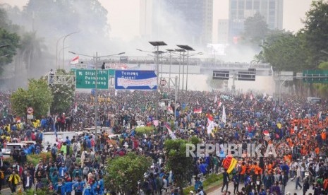 Asap gas air mata mengepul dari kejauhan saat mahasiswa memblokade jalan tol dalam pada aksi di depan Kompleks Gedung Parlemen RI, Selasa (24/9).