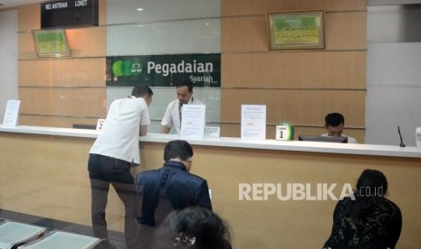 Petugas melayani nasabah ketika bertransaksi di kantor pelayanan Pegadaian Syariah, Jakarta, Jumat (4/1). Tiga tahun terakhir, omzet Pegadaian syariah mengalami tren peningkatan.