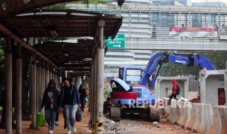 Warga berjalan kaki di dekat proyek penataan trotoar di kawasan Sudirman, Jakarta Pusat, Jumat (29/6).