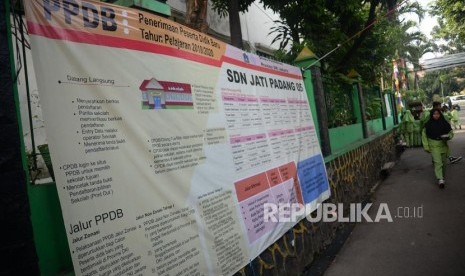 Anak-anak melintas didekat pengumuman Penerimaan Peserta Didik Baru (PPDB) online tahun pelajaran 2019/2020 yang dipajang di SDN Jati Padang 05, Jakarta, Jumat (14/6).