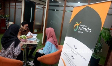 Karyawan memberikan informasi produk kepada calon pesesrta di kantor Asuransi Jasindo Syariah, Jakarta.