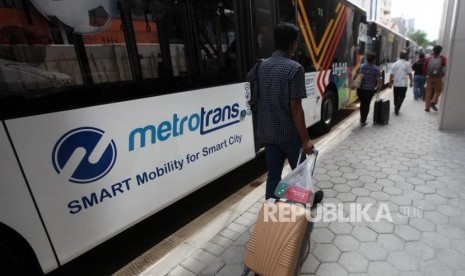 Warga berjalan disamping bus Metrotrans saat uji coba integritas Transjakarta.