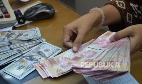 Petugas menghitung mata uang rupiah dan dolar AS di salah satu tempat penukaran uang di Jakarta. (ilustrasi)