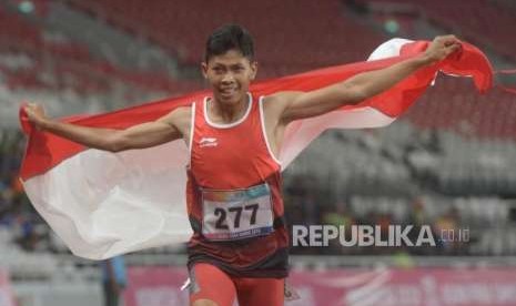 Sprinter Indonesia Sapto Yogo Purnomo berlari sambil membawa bendera Merah-Putih usai menjuarai final 100 meter putra T37 Asian Para Games di Stadion Utama Gelora Bung Karno, Senayan, Jakarta, Selasa  (9/10).