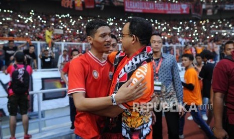 Gubernur DKI Jakarta Anies Baswedan memeluk seorang suporter Persija Jakarta seusai laga melawan Mitra Kukar di Liga 1 2018 di Stadion Utama Gelora Bung Karno, Jakarta, Ahad (9/12).