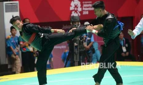 Pesilat Indonesia Komang Harik Adi Putra (pita merah) bertanding melawan pesilat Malaysia Mohd Al Jufferi Jamari pada babak final cabang pencak silat putra kelas E 65-70 kg Asian Games 2018 di Padepokan Pencak Silat,TMII, Jakarta, Senin (27/8).