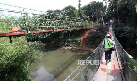 Pekerja melintas disamping pembangunan jembatan gantung di kawasan Srengseng Sawah, Jagakarsa, Jakarta, Jumat (3/8).