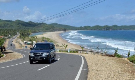 Kendaraan melintas di Jalan Lintas Pantai Selatan di tepi pantai Soge, Ngadirejo, Pacitan, Jatim. Pemprov Jatim menargetkan jalur selatan Pacitan-Banyuwangi terhubung dalam 5 tahun.