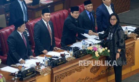 Menteri Keuangan Sri Mulyani (depan) berjabat tangan dengan Wakil Ketua DPR Taufik Kurniawan (tengah) disaksikan Pimpinan DPR lainnya saat pengambilan keputusan RUU dalam rapat paripurna DPR di Kompleks Parlemen, Senayan, Jakarta, Kamis (26/4).