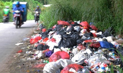 Sejumlah kendaraan melintas didekat sampah yang dibuang di pinggir jalan di kawasan Bojong Depok Baru, Cibinong, Bogor, Jawa Barat, Selasa (24/4).