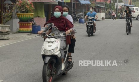 Warga mengendarai motor saat asap kebakaran lahan gambut menyelimuti Alun-alun Kabupaten Siak, Riau, Kamis (12/9).