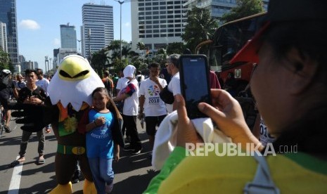 Seorang anak berfoto dengan maskot Asian Paragames Momo   dikawasan hari bebas berkendara / Car Free Day di Bundaran HI, Jakarta (1/4).