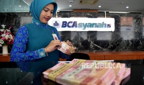 Petugas menghitung uang nasabah ketika transaksi di kantor layanan BCA Syariah, Jakarta, Selasa (6/11).