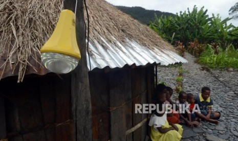 LTSHE. Warga beraktivitas di dekat rumah adat honai yang telah terpasang  jaringan Lampu Tenaga Surya Hemat Energi (LTSHE ) di Kabupaten Puncak Jaya, Papua, Jumat (15/3).